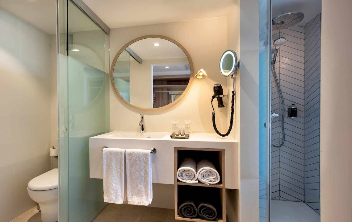 Badezimmer im Guayarmina Princess Hotel mit Rundspiegel, Waschbecken, Föhn und Dusche