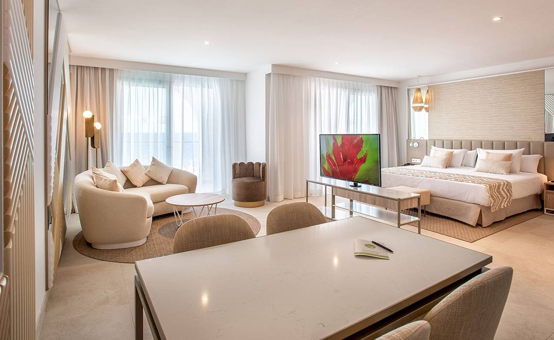 Schlafzimmer im Guayarmina Princess Hotel mit einem großen Bett, Couch, Tisch und Fernseher.