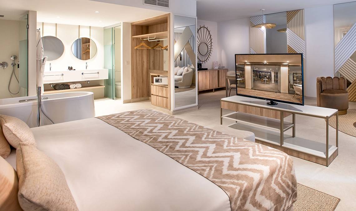 Innenansicht der Suite im Guayarmina Princess Hotel mit Bett, Fernseher und Badezimmer.