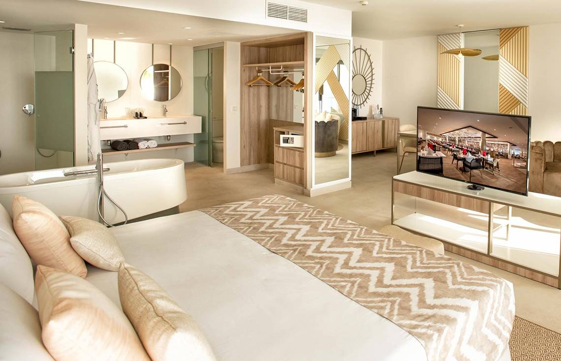 Innenansicht eines Zimmers im Guayarmina Princess Hotel mit Bett, Badewanne und Fernseher.