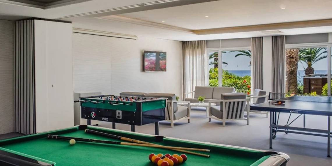 Spielzimmer im Alion Beach Hotel mit Billardtisch, Tischtennisplatte und Sofas.