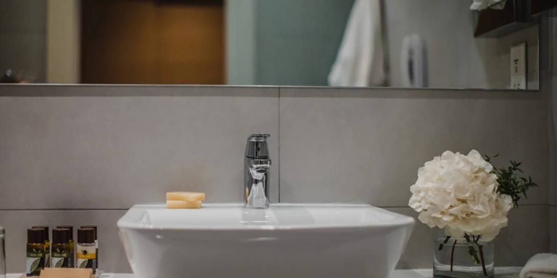 Badezimmer im Alion Beach Hotel mit Waschbecken, Seife und Blumen.