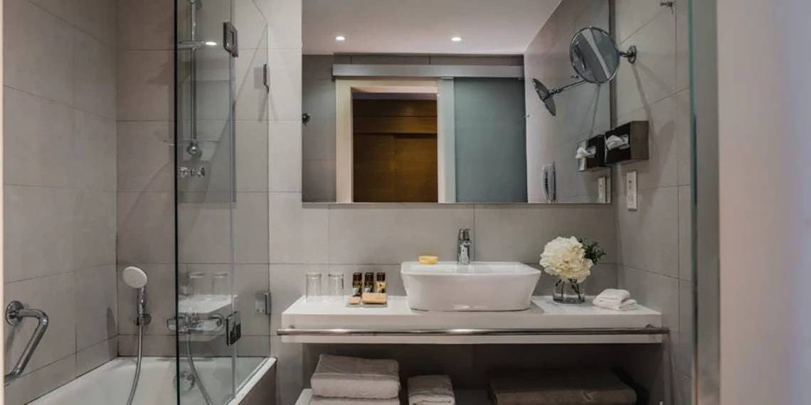 Modernes Badezimmer im Alion Beach Hotel mit Badewanne, Waschbecken und Glasdusche
