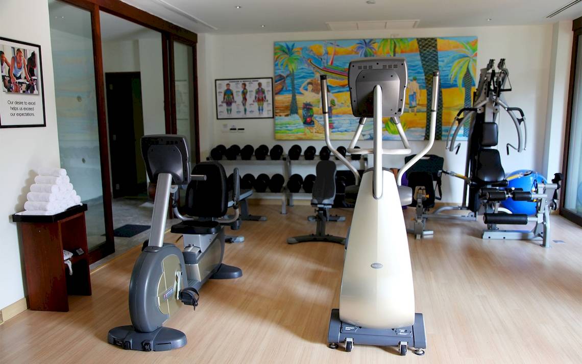 Fitnessraum im Mai Samui Beach Resort & Spa mit Trainingsgeräten und einer Wandmalerei.