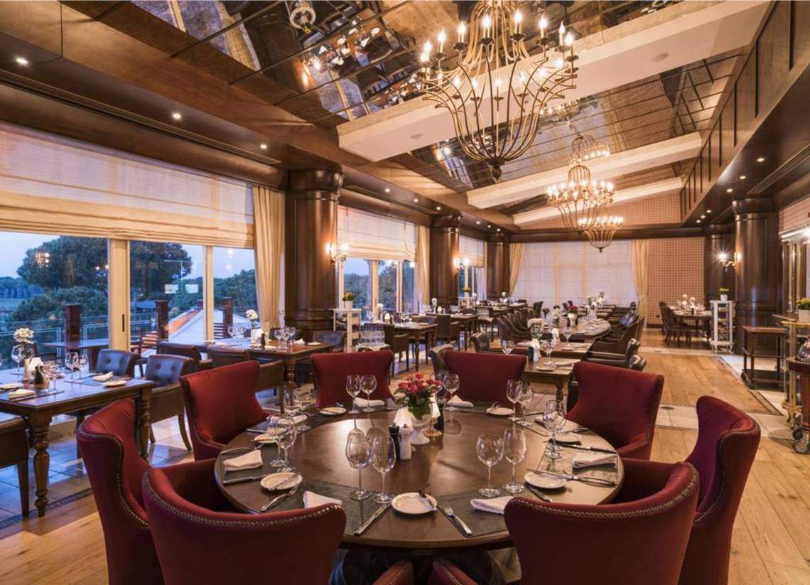 Innenbereich des Restaurants im Maxx Royal Belek Golf Resort mit eleganten Tischstühlen und kristallenen Kronleuchtern.
