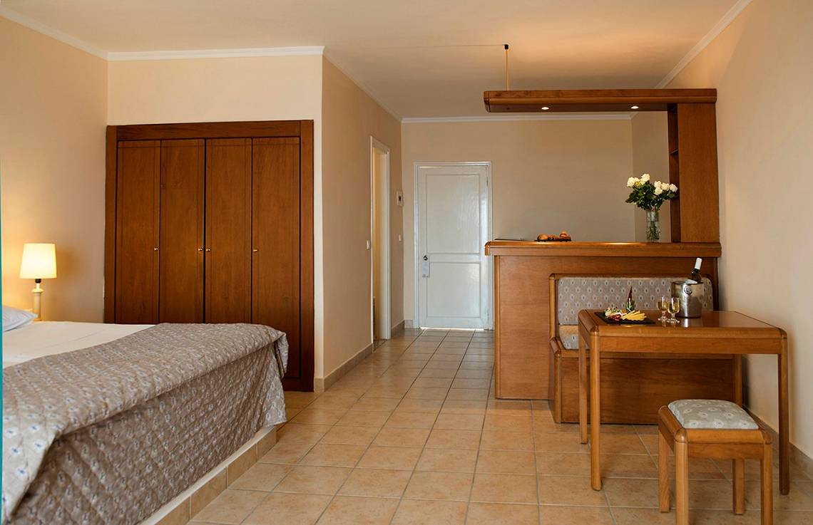 Schlafzimmer im Mitsis Family Village Beach Hotel mit Bett, Schrank, Tisch und Dekoration.