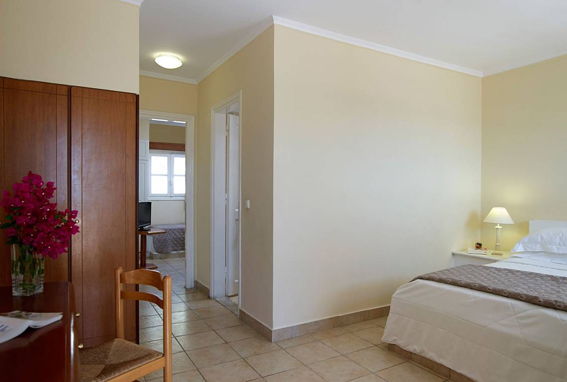 Schlafzimmer im Mitsis Family Village Beach Hotel mit Bett, Nachttisch und Dekor.