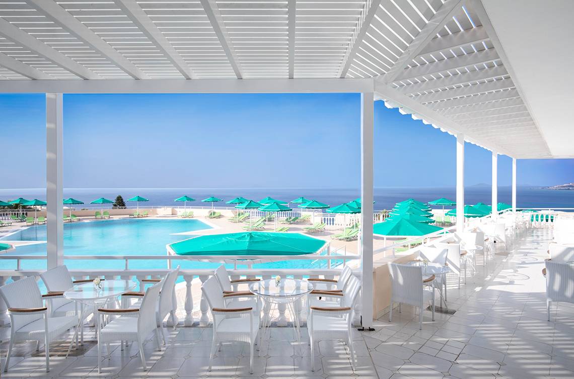 Terrasse des Mitsis Family Village Beach Hotels mit Blick auf den Pool und das Meer