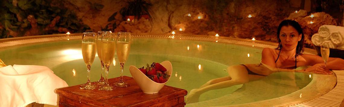 Eine Frau genießt ein Getränk in einem beleuchteten Whirlpool mit Champagner und Erdbeeren.