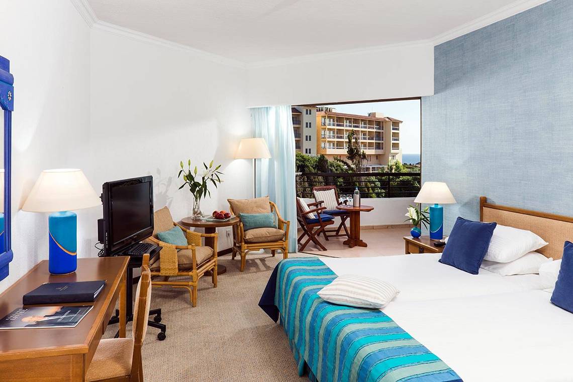 Zimmer im Coral Beach Hotel mit Meerblick und Balkonmöbeln.