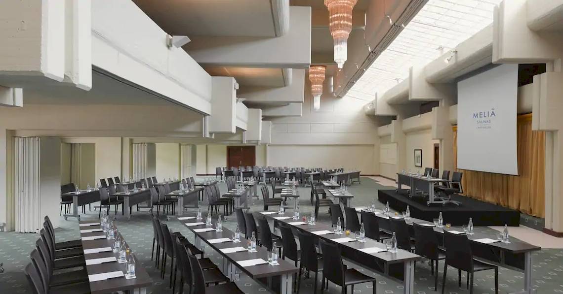 Konferenzsaal im Melia Salinas Hotel mit vielen Tischen, Stühlen und einer Leinwand