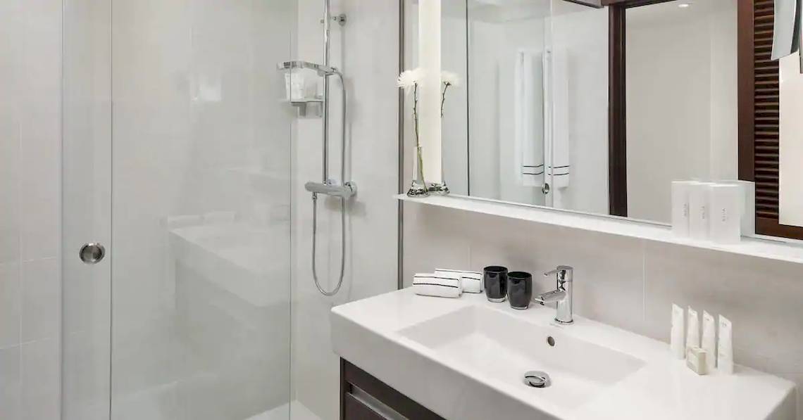 Badezimmer im Melia Salinas Hotel mit ebenerdiger Dusche, Waschbecken und Spiegel.