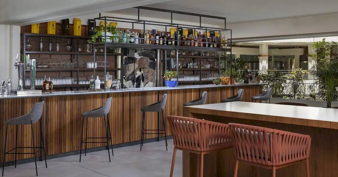Innenansicht der Bar im Melia Salinas Hotel mit Barhockern, Holztheke und Regalen voller Flaschen.