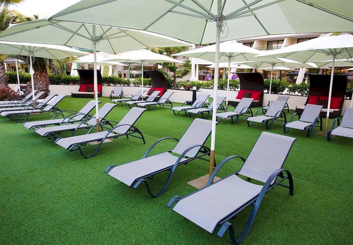 Lounge-Bereich im Dreams Lanzarote Playa Dorada Resort & Spa mit vielen Liegestühlen und Sonnenschirmen.