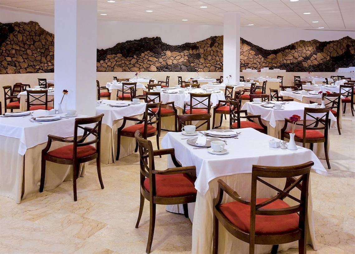 Speisesaal des Dreams Lanzarote Playa Dorada Resort & Spa mit weißen Tischen und roten Stühlen.
