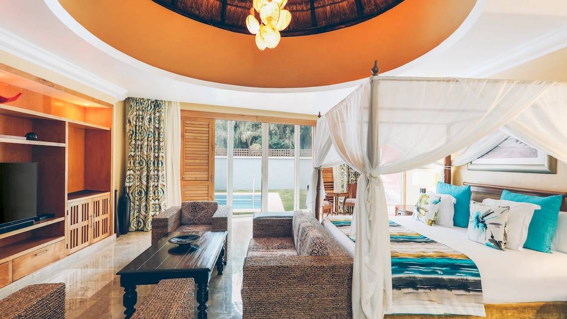 Innenansicht der Suite im Iberostar Grand Paraiso mit Bett, Fernseher und Möbeln.