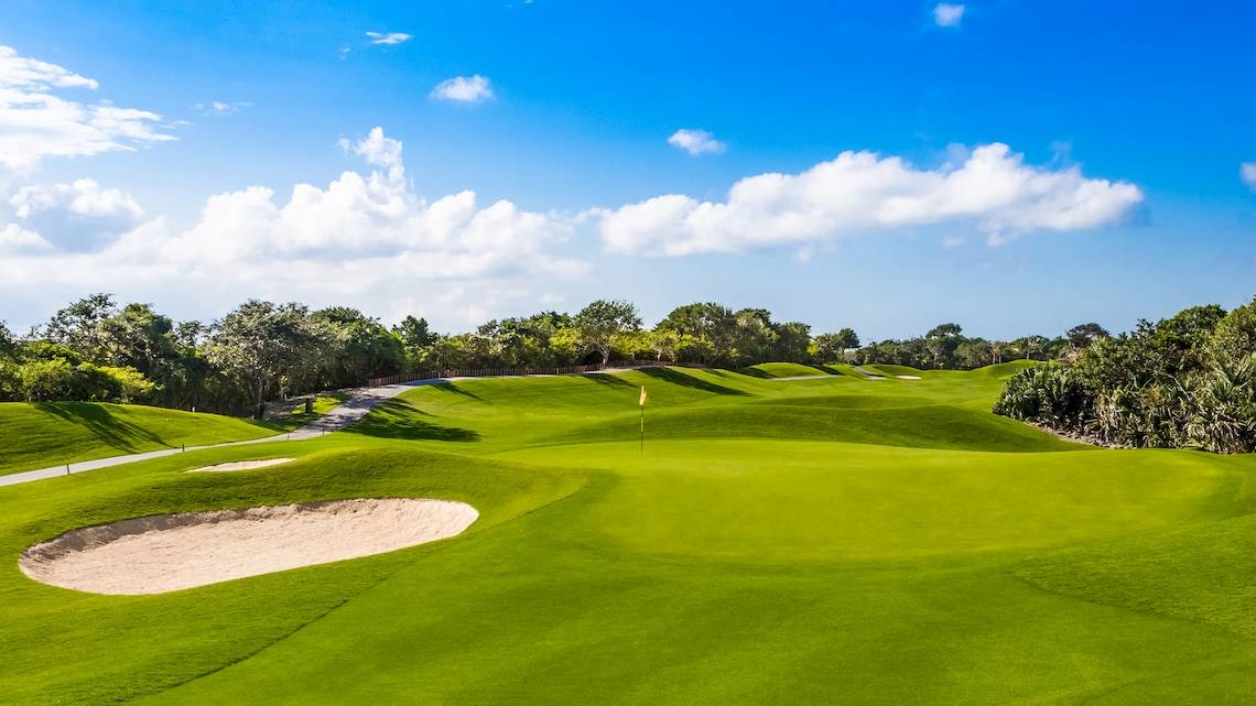 Golfplatz des Iberostar Grand Paraiso Hotels mit grünen Rasen und Bäumen.