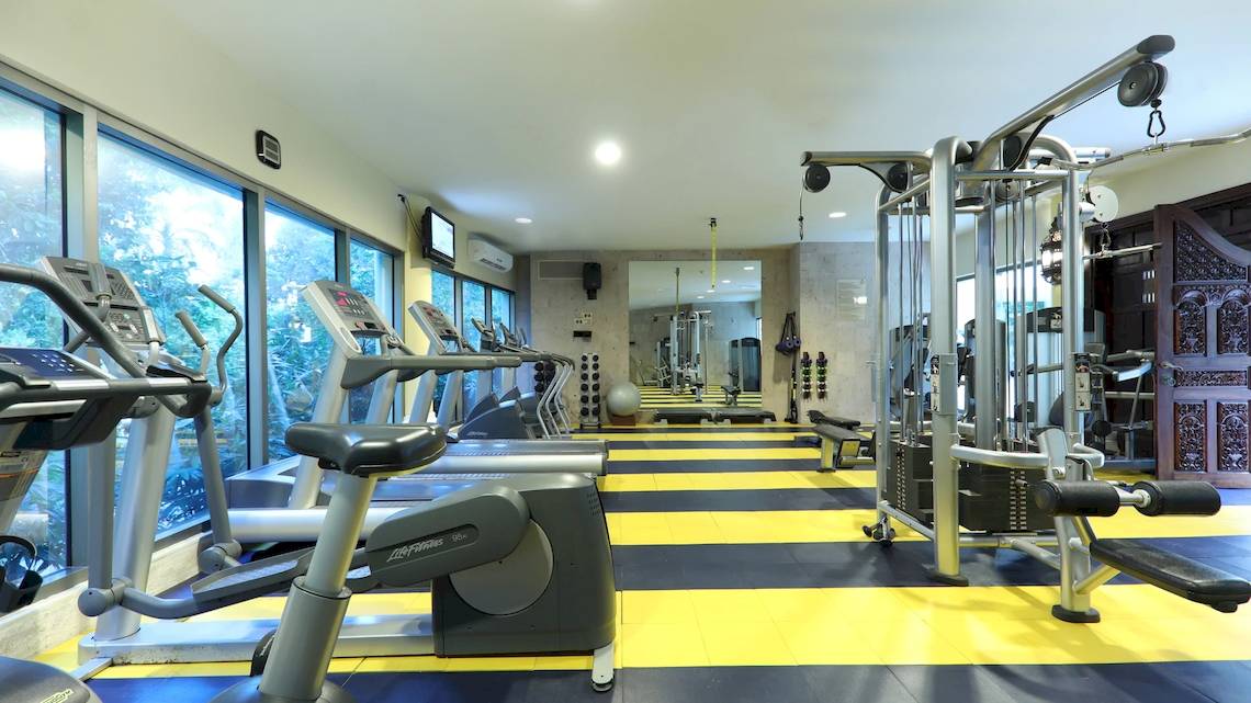 Fitnesscenter im Iberostar Grand Paraiso Hotel mit Laufbändern, Kraftgeräten und großen Fenstern.