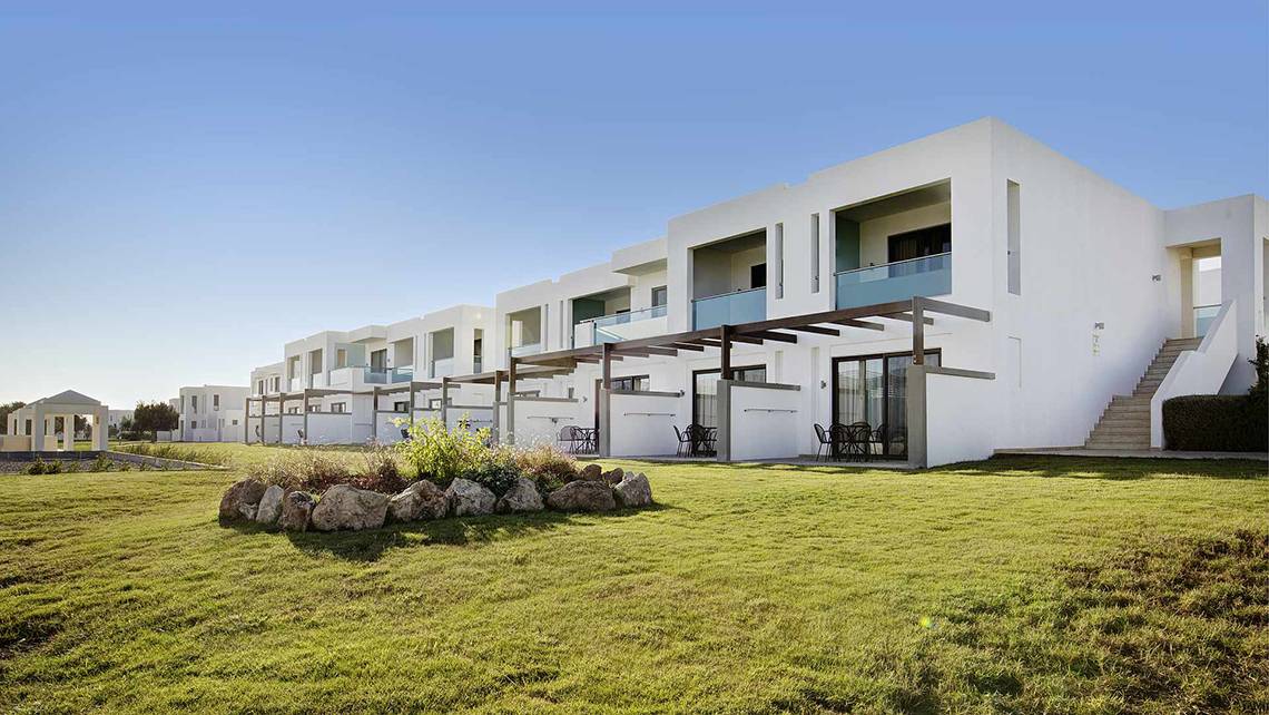 Außenansicht des Club Plimmiri Hotels mit weißen Gebäuden und grünem Rasen