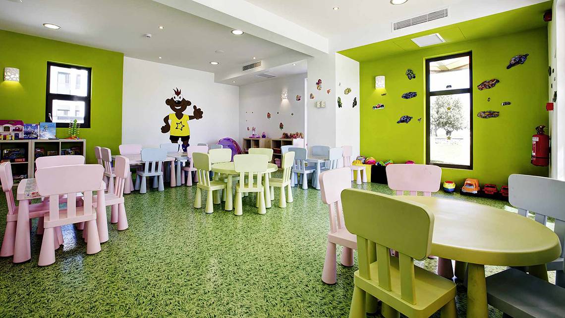 Kinderspielzimmer im Club Plimmiri Hotel mit grünen Wänden, bunten Möbeln und Spielsachen.