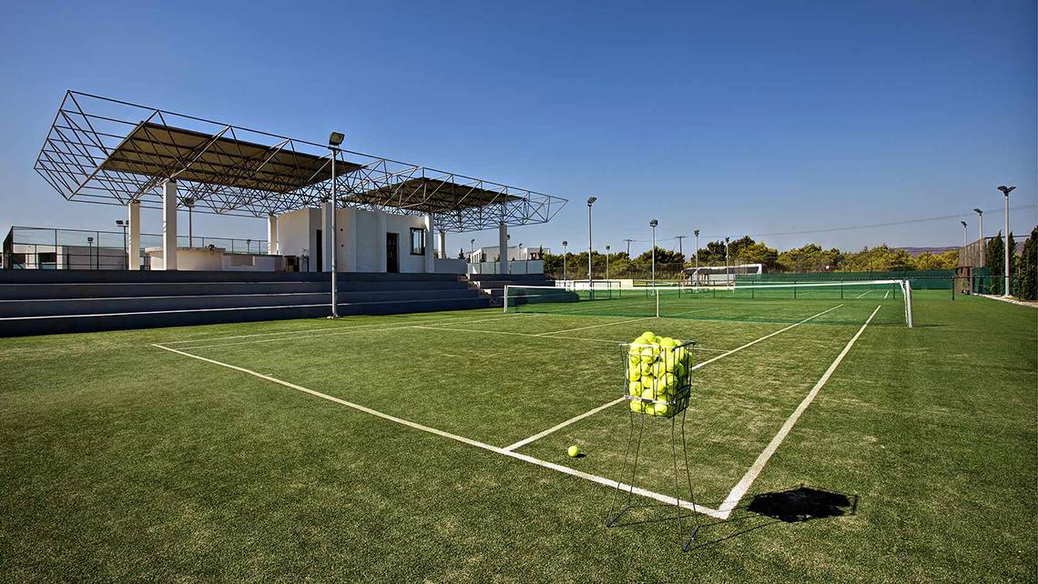 Tennisplatz des Club Plimmiri Hotels mit leeren Bänken und einem Ballkorb auf dem Feld