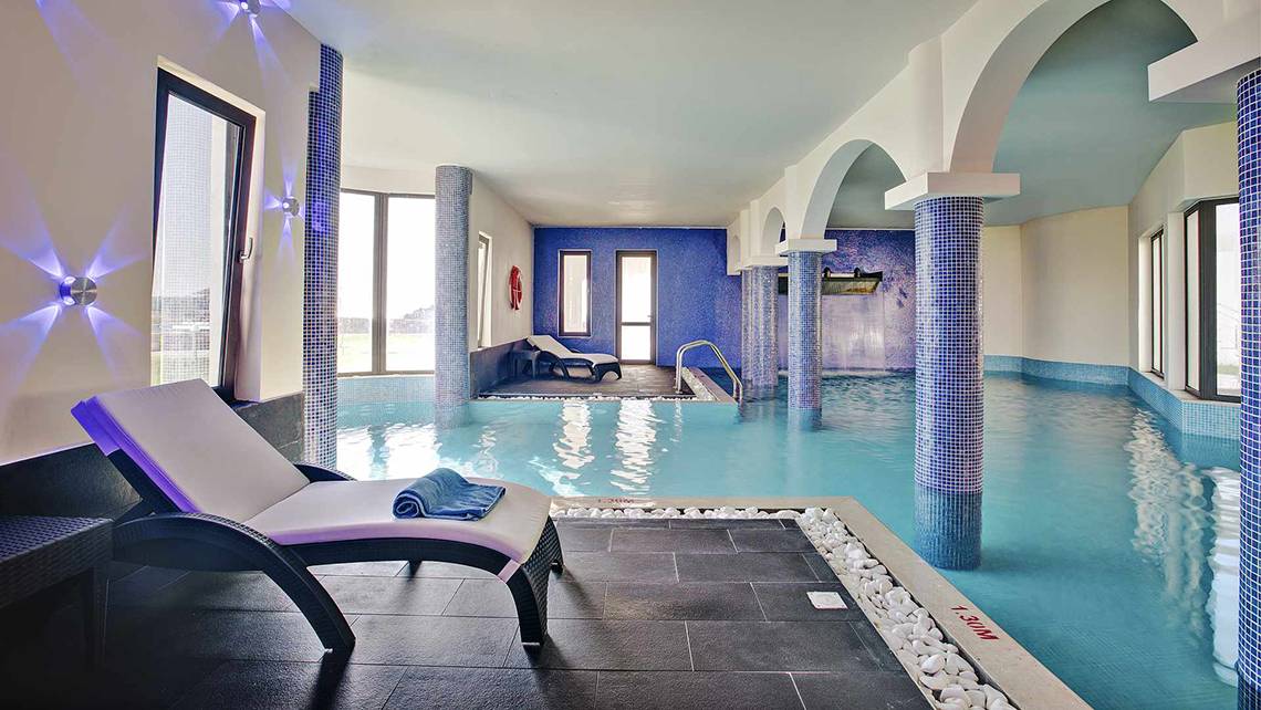 Pool-Loungebereich im Club Plimmiri Hotel mit blauen Säulen und Liegestühlen.