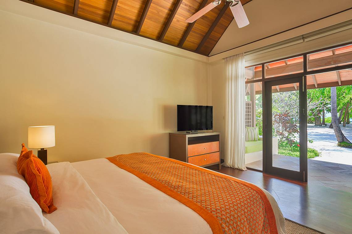 Schlafzimmer im Kurumba Maldives mit Bett, Fernseher und Balkonzugang