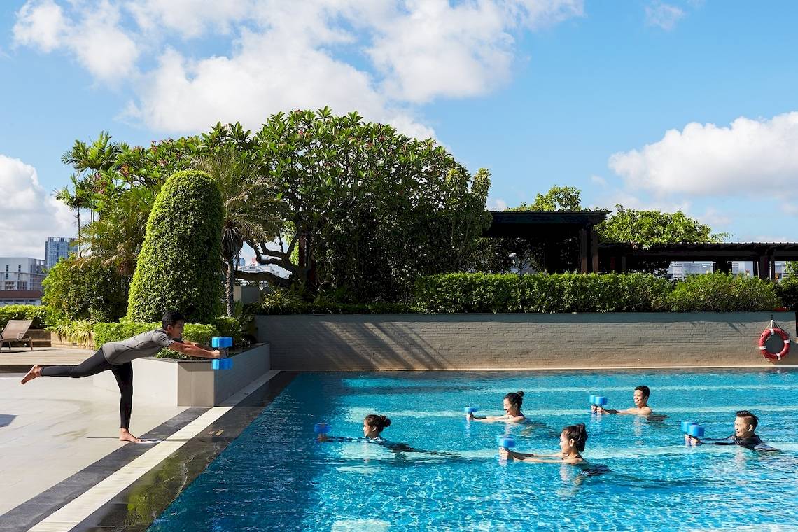 Training im Schwimmbecken des Pathumwan Princess Hotels mit Teilnehmern, die Wassergymnastik machen.