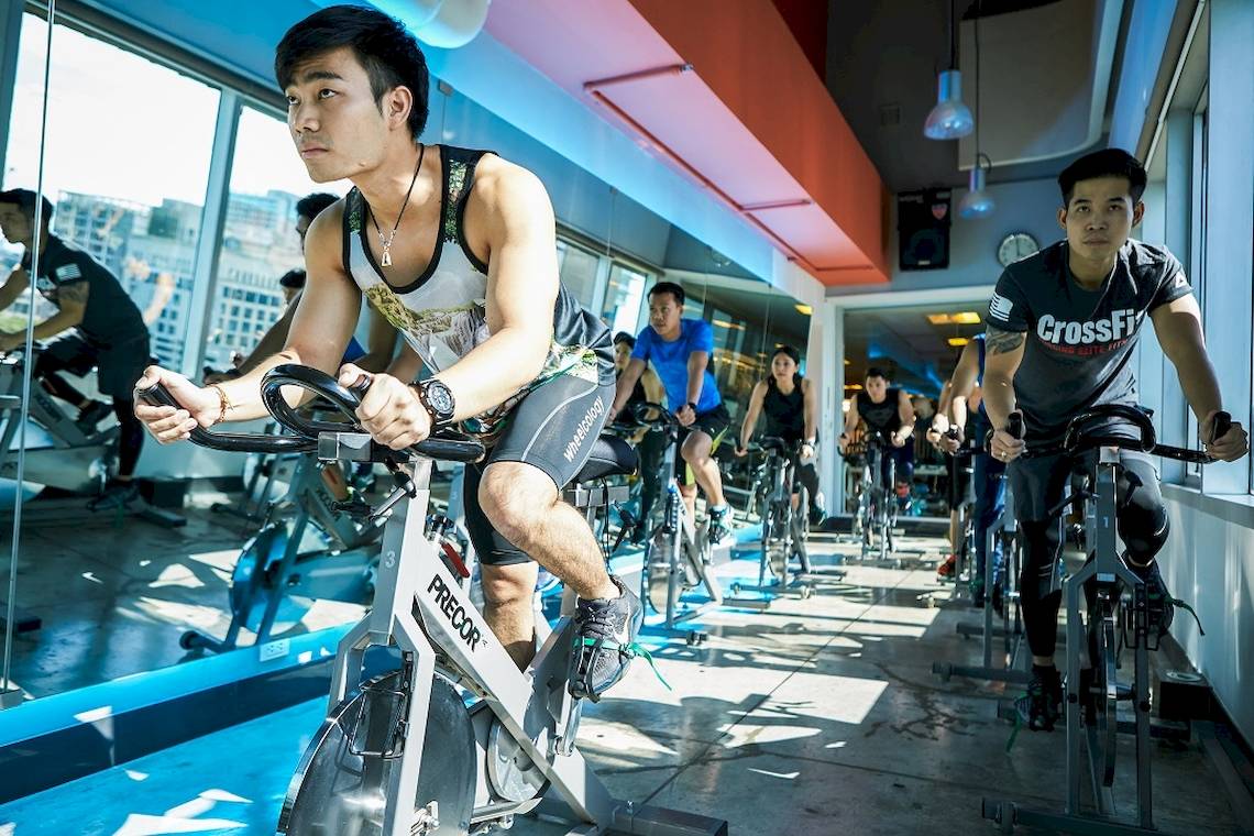 Gruppe von Männern, die in einem Fitnessstudio des Pathumwan Princess Hotels auf Spinrädern trainieren.