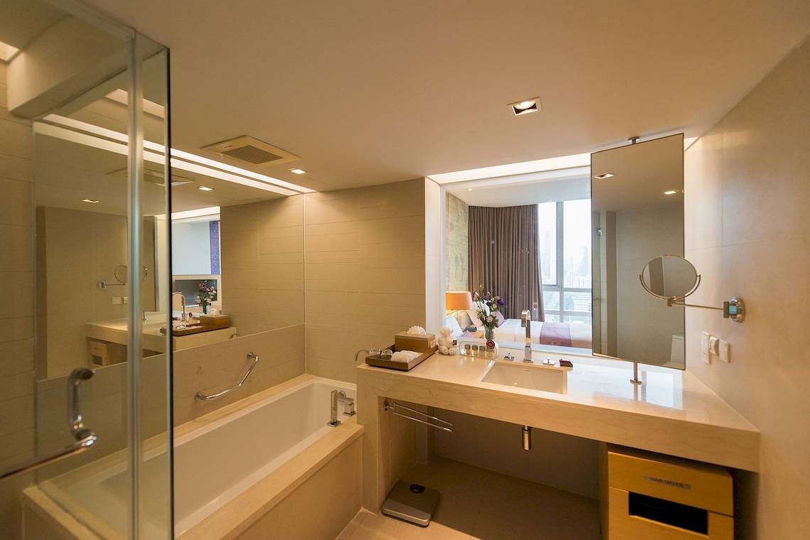 Badezimmer im Pathumwan Princess Hotel mit Badewanne, Spiegel und Waschbecken.