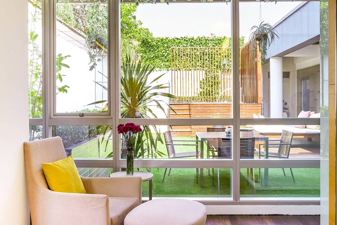 Innenansicht des Pathumwan Princess Hotels durch große Fenster mit Gartenblick