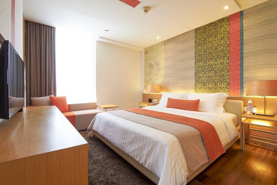 Pathumwan Princess Hotelzimmer mit Doppelbett, Fernseher und Sitzbereich.