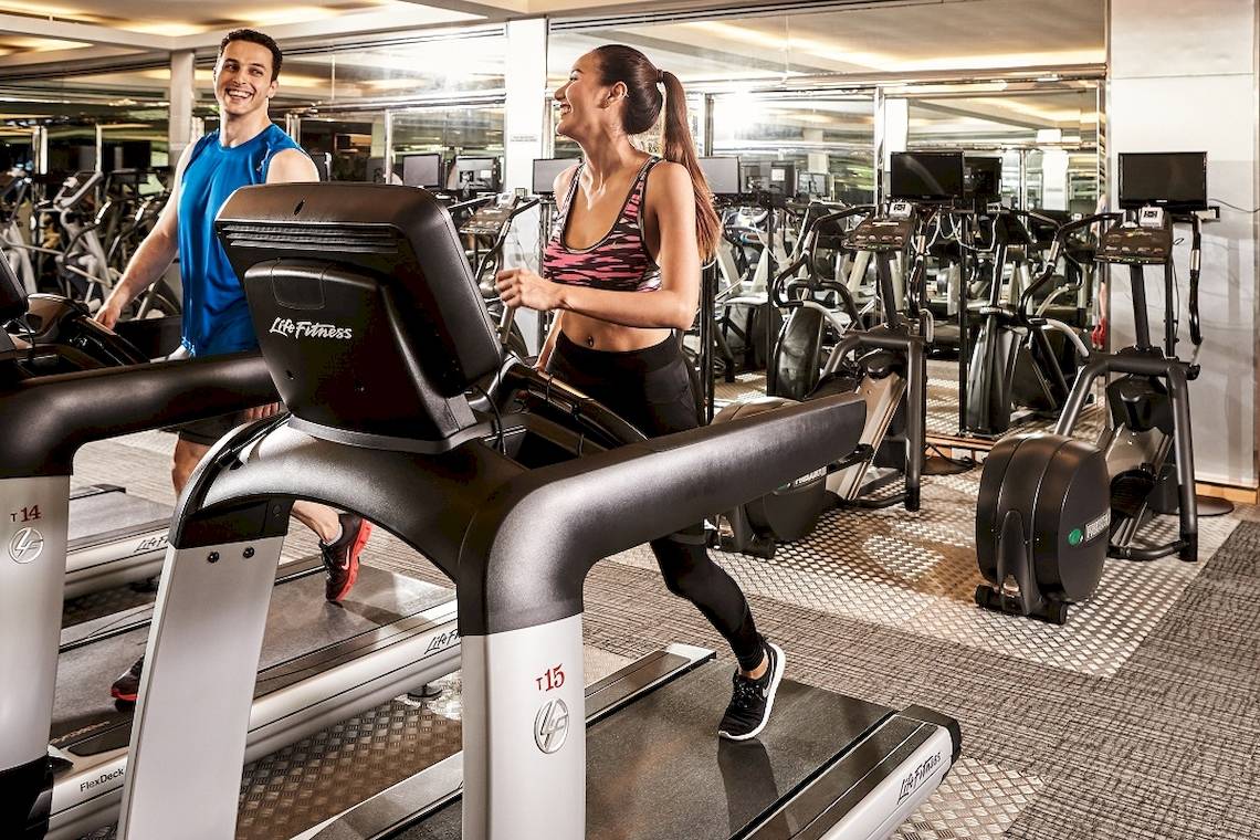 Fitnessstudio im Pathumwan Princess Hotel mit Männern und Frauen auf Laufbändern