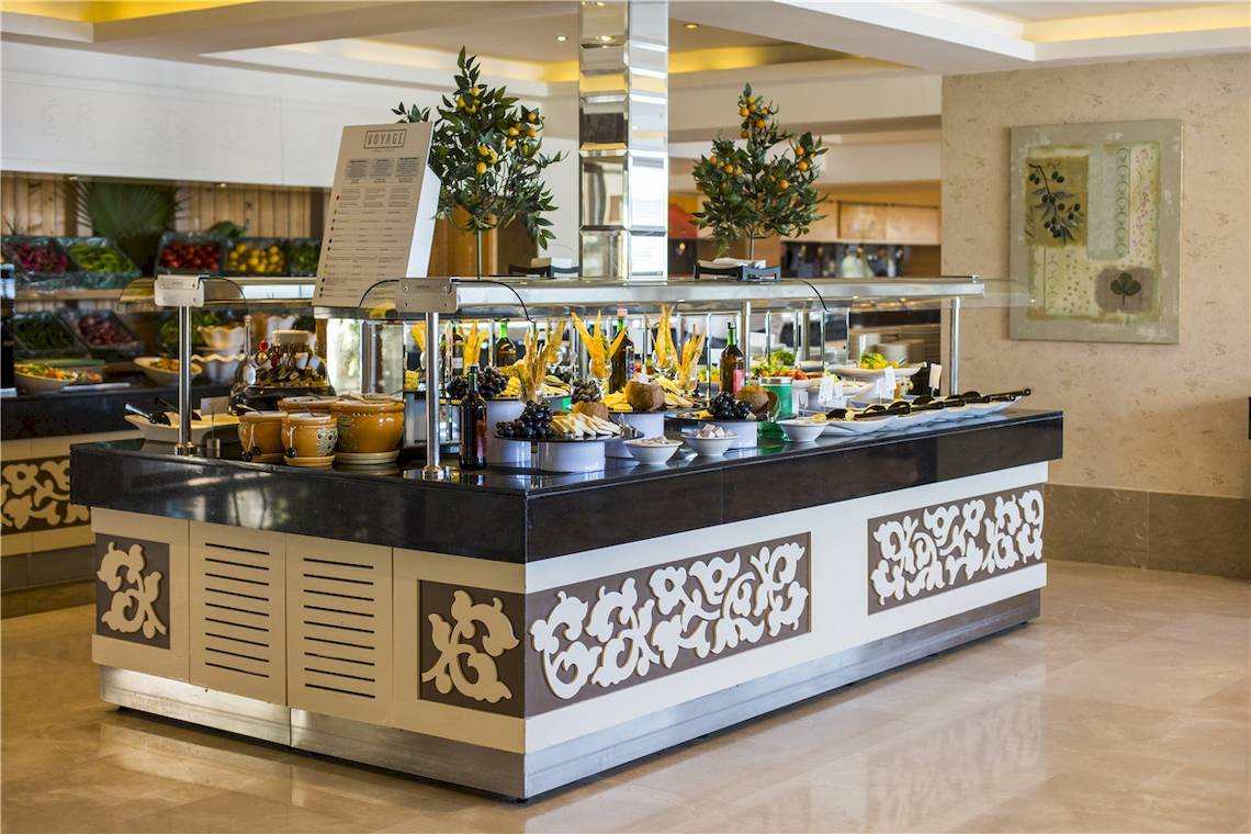 Buffettisch im Voyage Torba Hotel mit verschiedenen Gerichten und Pflanzen.