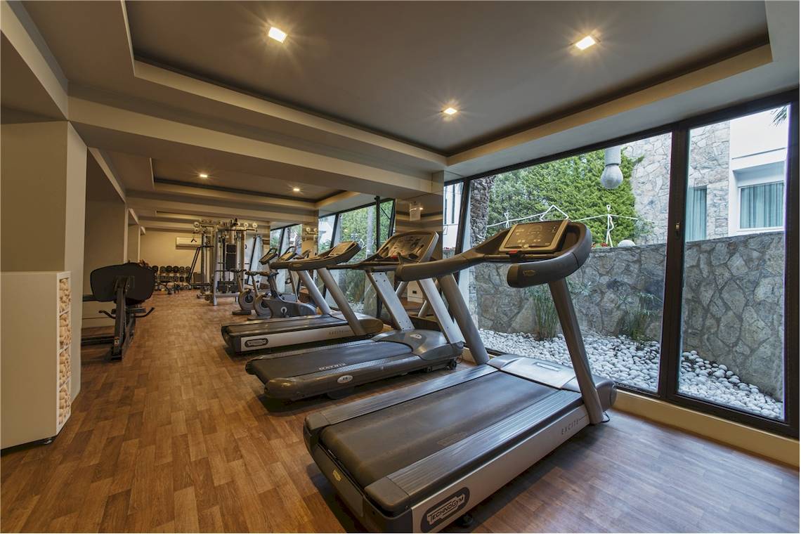 Fitnessstudio im Voyage Torba Hotel mit mehreren Laufbändern und Fitnessgeräten.