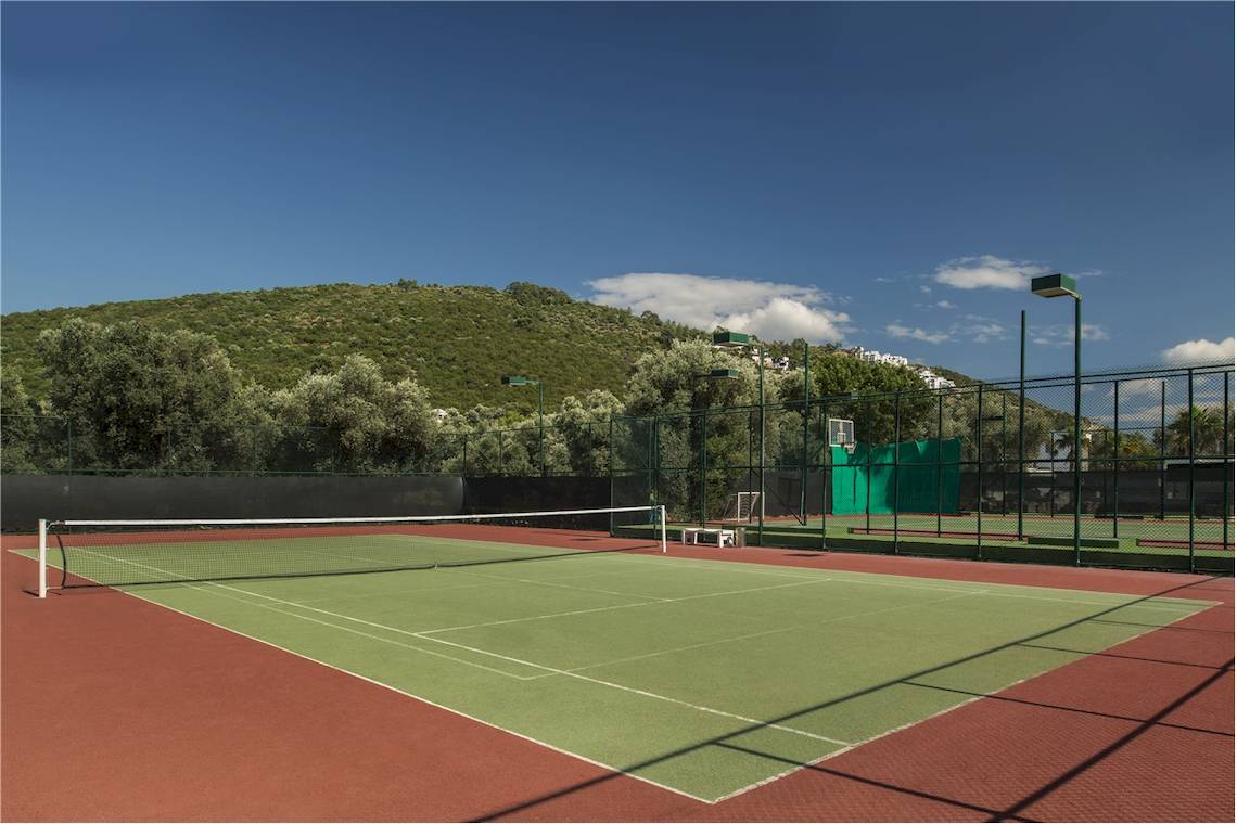 Tennisplatz im Voyage Torba Hotel mit grünem Platz und roten Seitenbereichen.