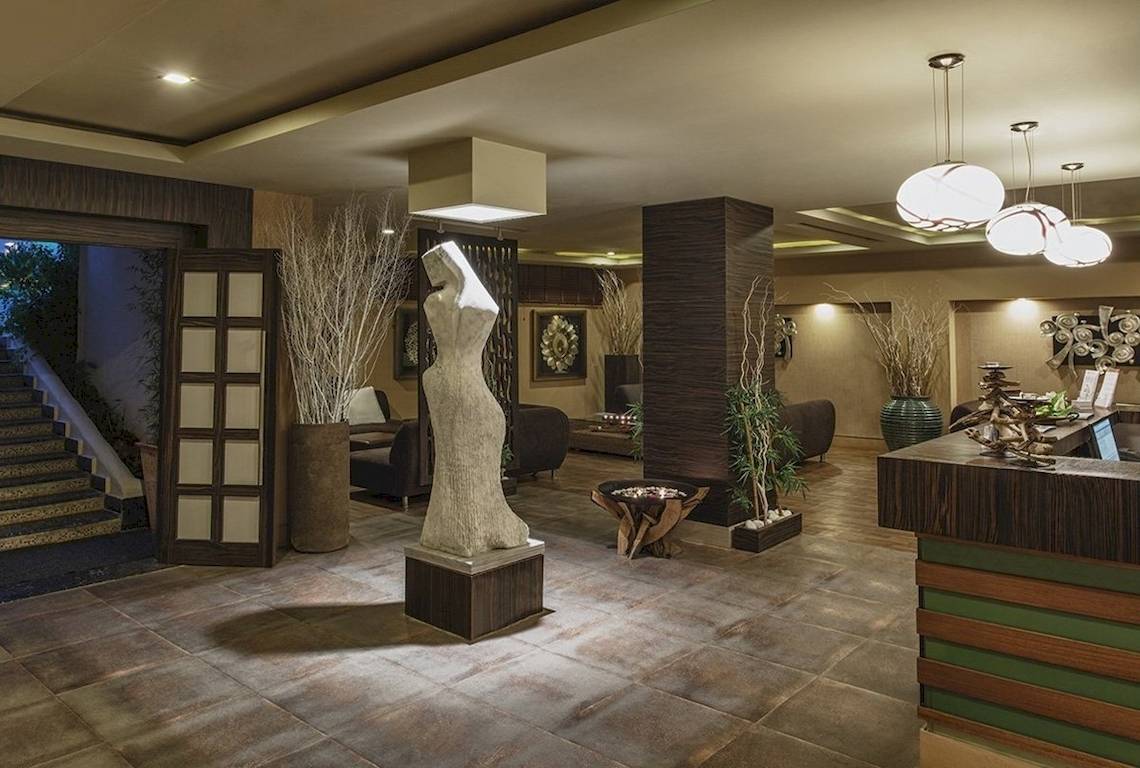 Innenansicht der Lobby des Voyage Torba Hotels mit einer Statue, Pflanzen und Möbeln.