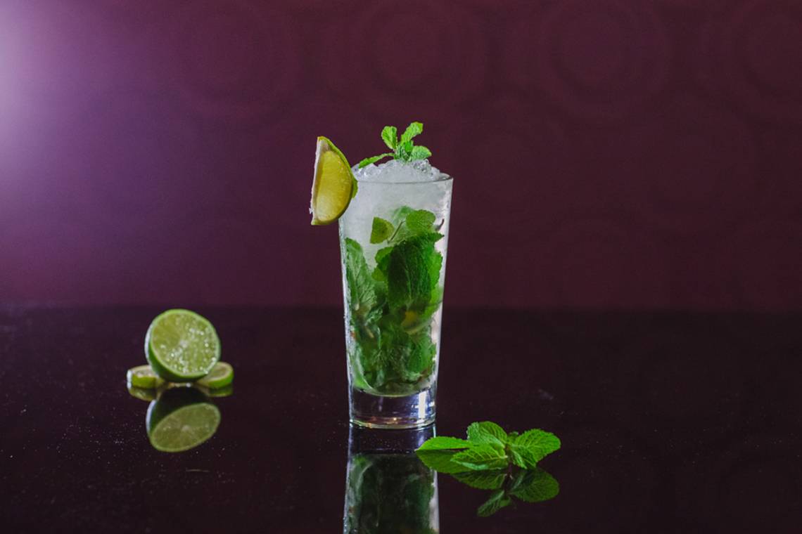 Cocktailglas mit Minze und Limette auf schwarzem Hintergrund
