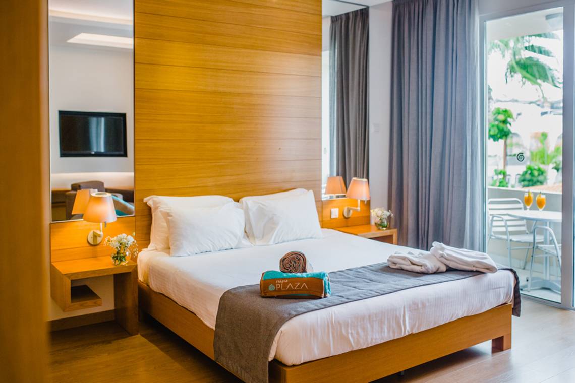 Doppelbettzimmer im Napa Plaza Hotel mit modernen Möbeln, Fernseher und Balkon.