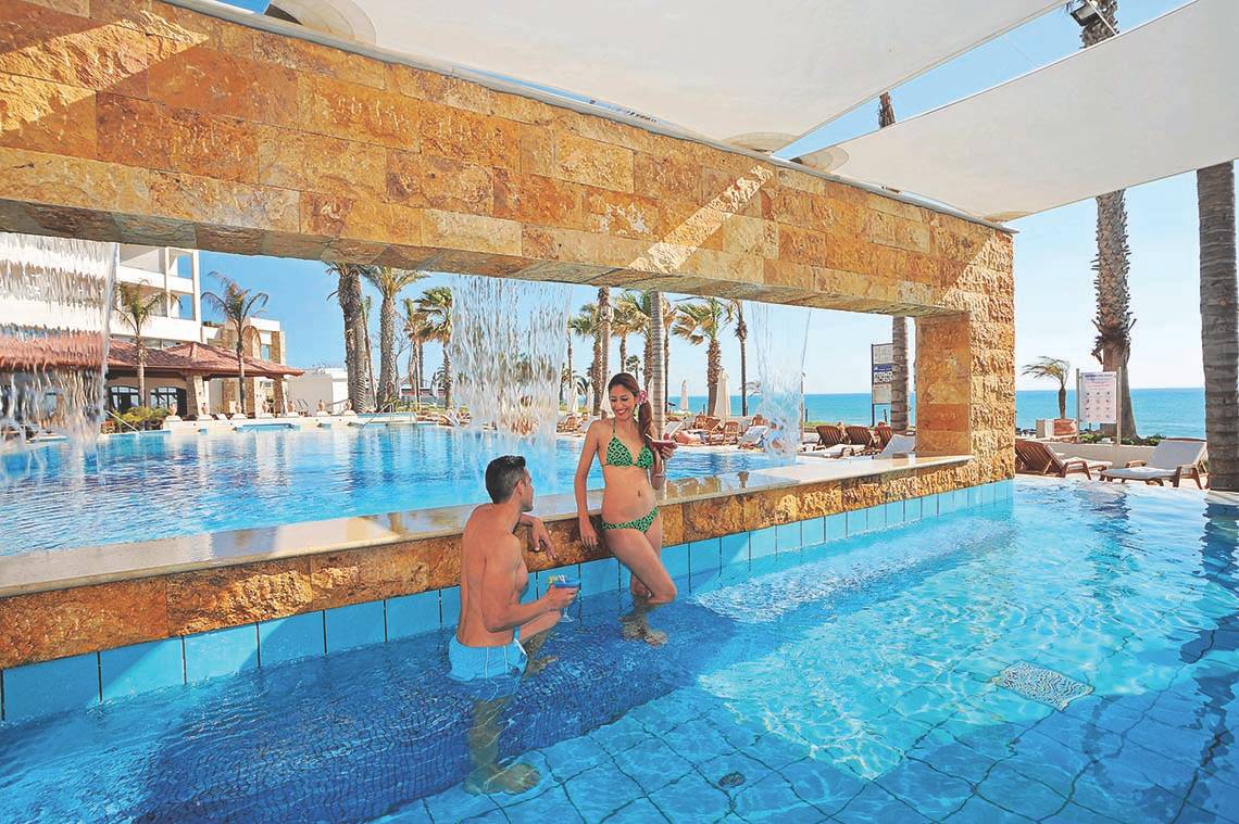 Ein Mann und eine Frau genießen den Pool im Alexander The Great Hotel.