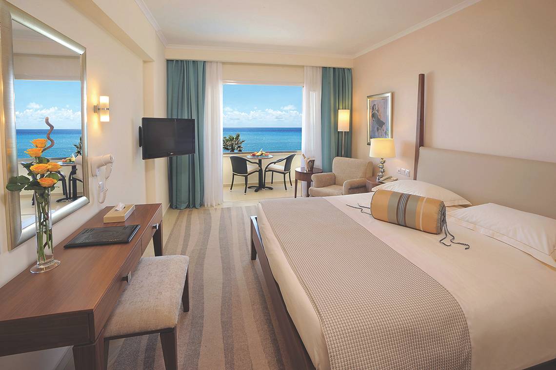 Zimmer im Alexander The Great Hotel mit Meerblick, Bett, Fernseher, Schreibtisch und Balkon