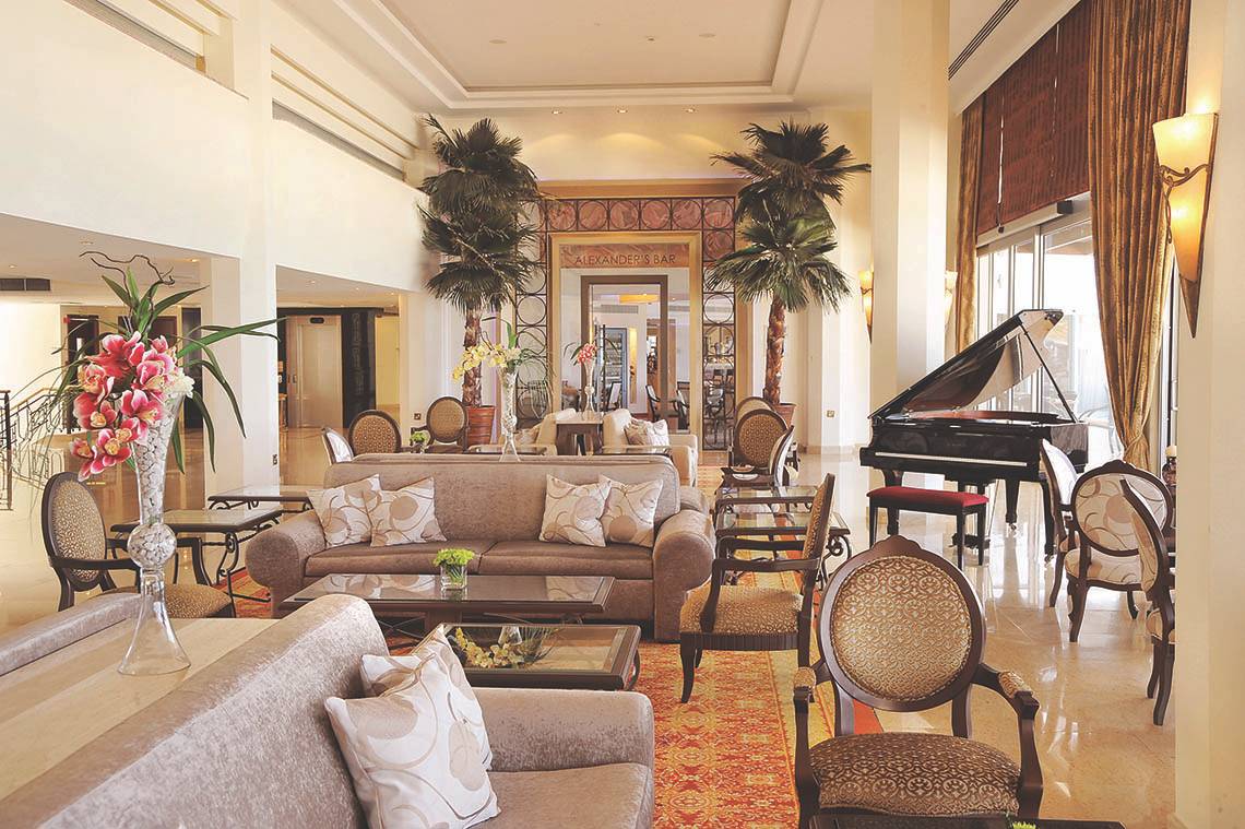Lobby des Alexander The Great Hotels mit Klavier, Sofas und Palmen.