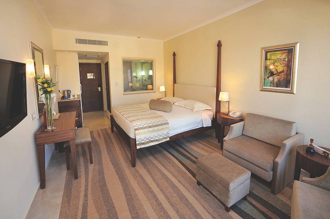 Hotelzimmer von Alexander The Great mit Doppelbett, Nachttischen, Fernseher und Dekor.