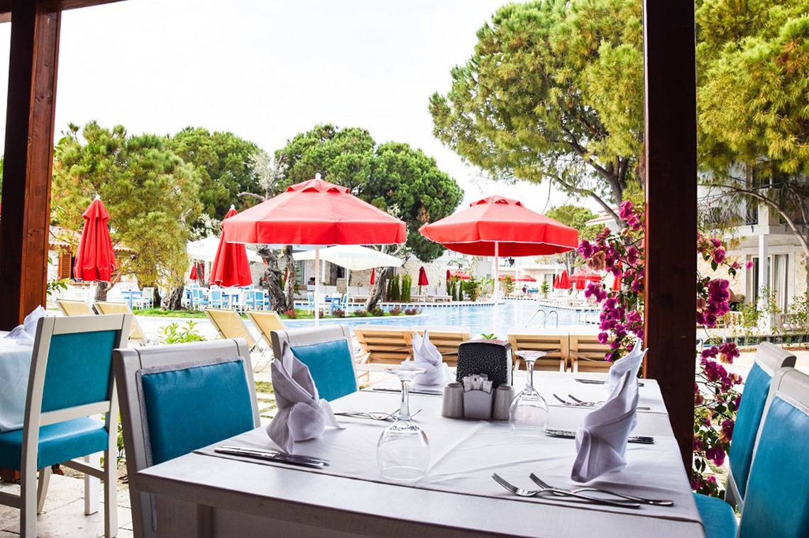 Ein Tisch im Restaurant mit roten Sonnenschirmen und Blick auf den Swimmingpool.