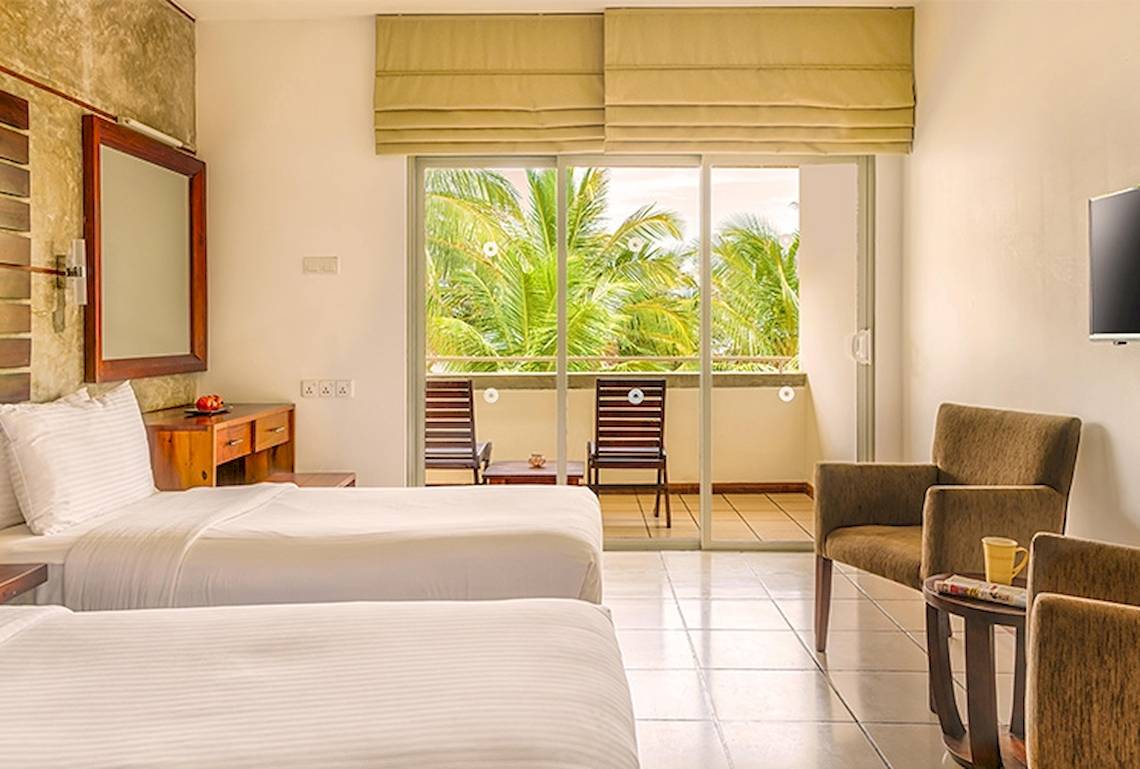 Doppelzimmer im Jetwing Sea Hotel mit Blick auf einen Balkon und zwei Betten