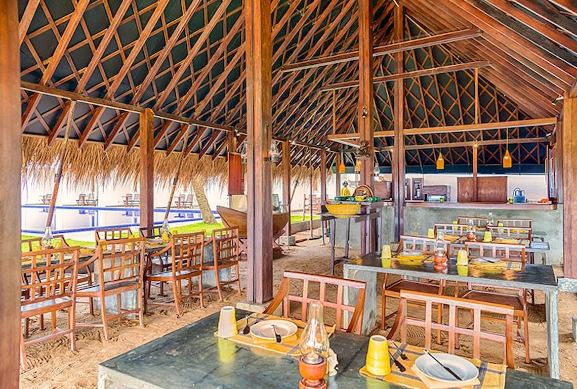 Innenansicht des Jetwing Sea Restaurants mit runden Tischen und Stühlen unter einem großen Dach.