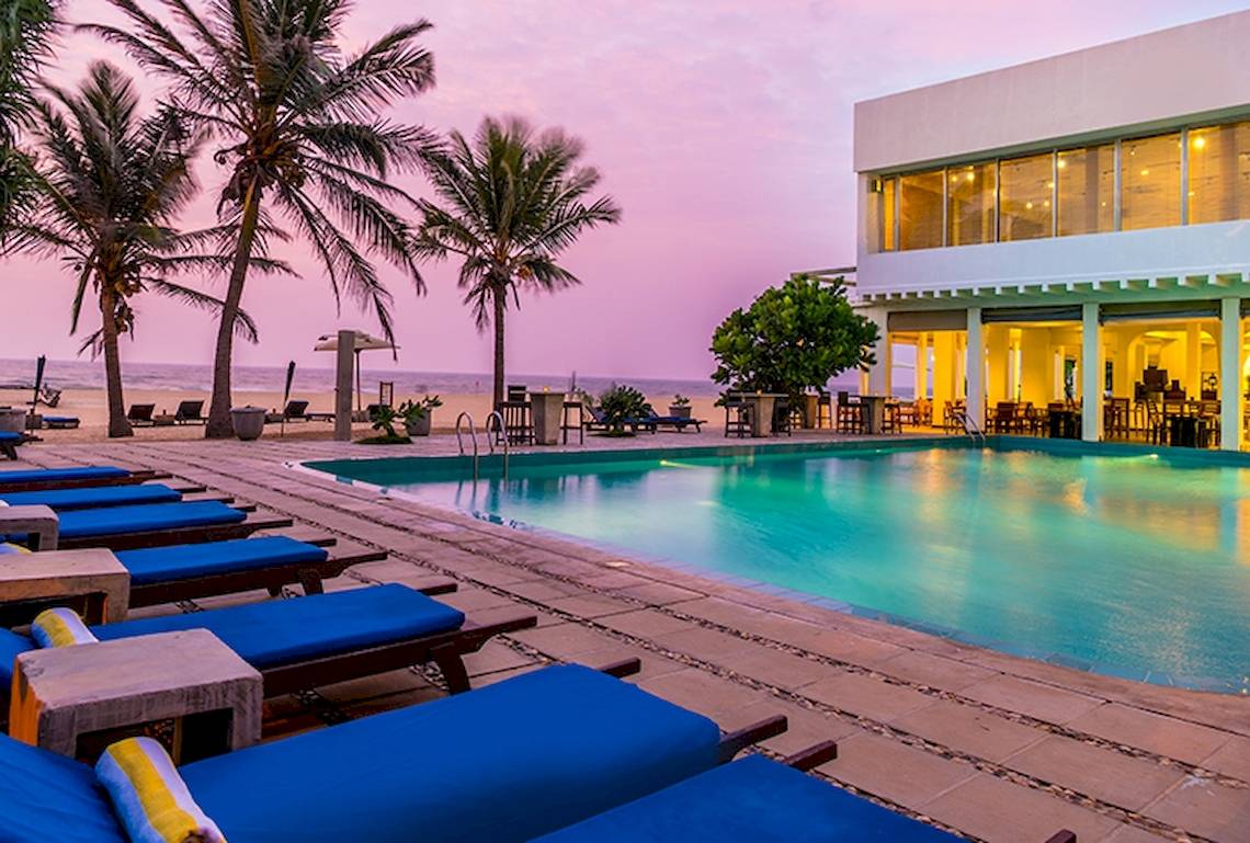 Am Abendansicht des Jetwing Sea Hotels mit Swimmingpool und Loungestühlen.
