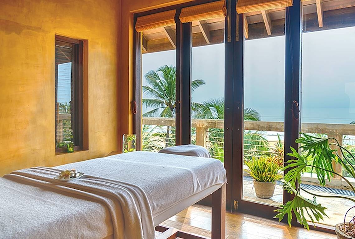 Massageraum im Jetwing Sea Hotel mit Blick auf das Meer und Palmen.