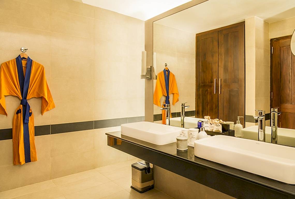 Badezimmer im Jetwing Sea Hotel mit zwei Waschbecken, Spiegel und gelben Kimonos