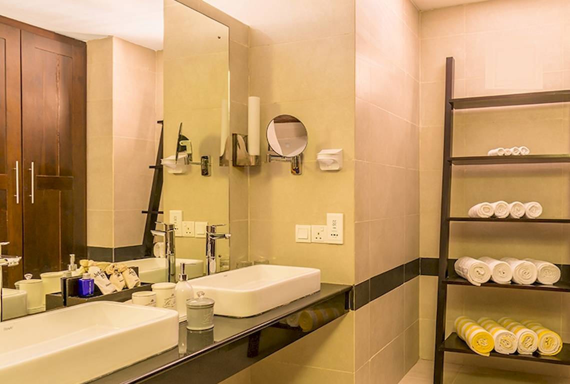 Badezimmer des Jetwing Sea Hotels mit zwei Waschbecken, Spiegel und Regal mit Handtüchern.